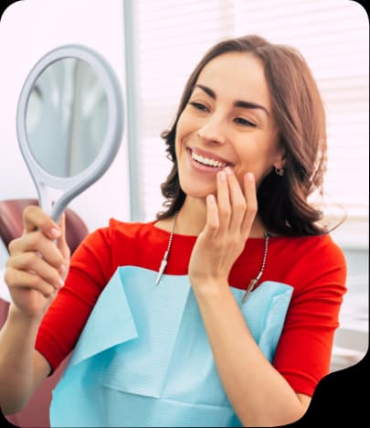 Patient checking her smile in a hand mirror in the dental chair
